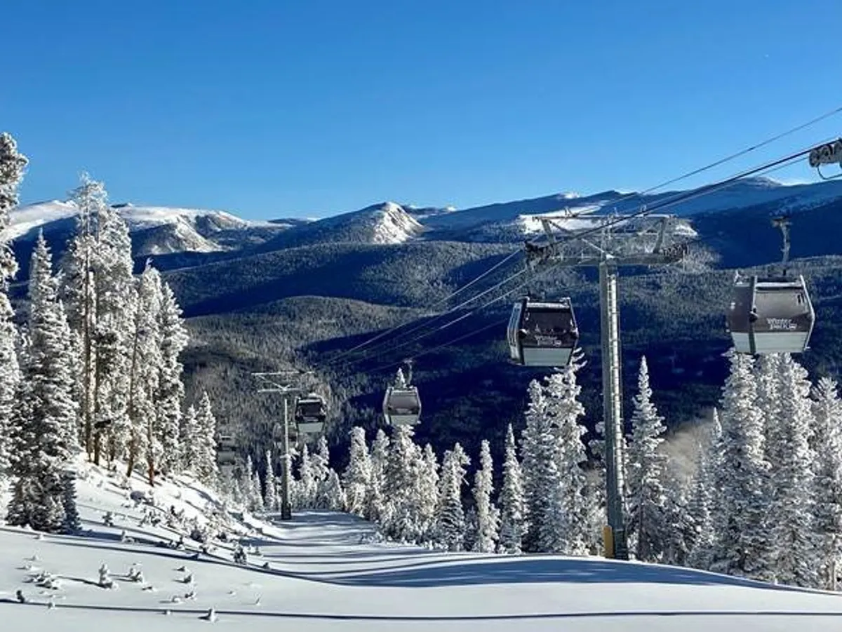 An exterior winter scene featuring ski lift gondolas ascending over snow-covered trees and ski slopes, set against a majestic mountain backdrop. The image evokes a sense of adventure and access to exclusive outdoor activities.