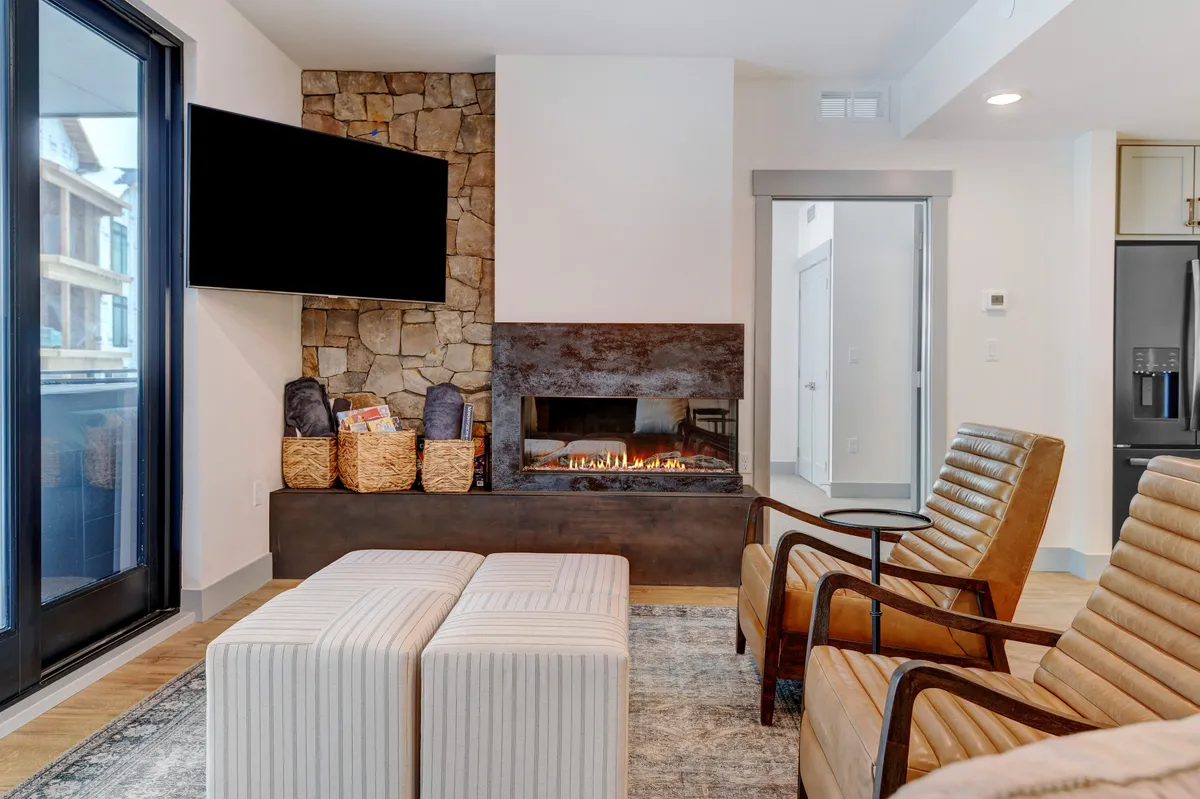 An inviting living room featuring a fireplace, comfortable seating area, a large television, and a textured stone wall—perfect for cozy movie nights and family gatherings after a day of exploring.