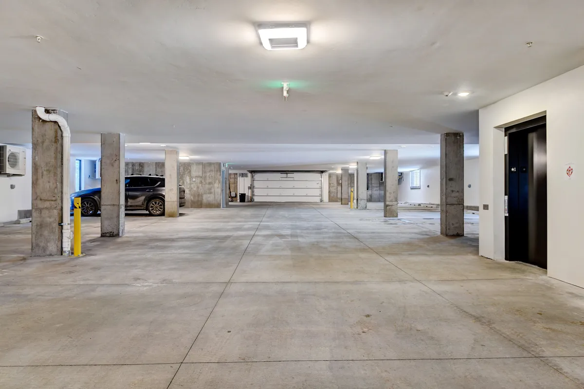 A functional interior image showing the building's parking spaces and elevators, emphasizing secure and convenient access for families arriving with children and equipment.